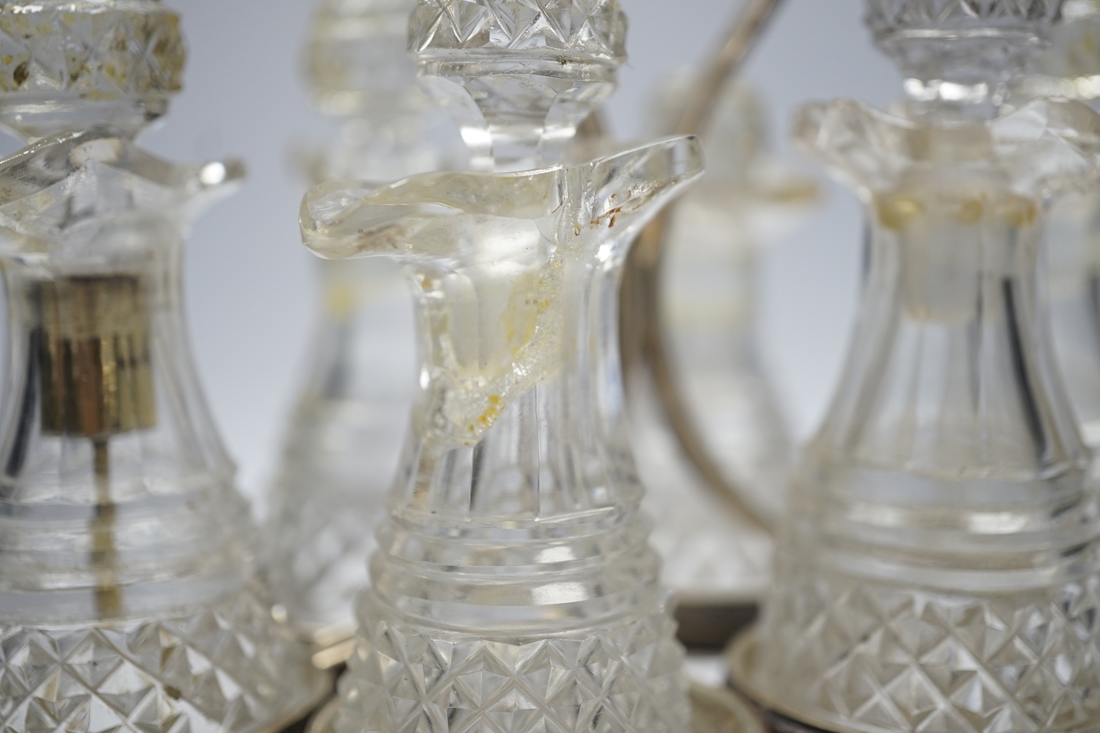 A George III silver mounted oval cruet stand, maker P?, London, 1802, with reeded ring handle and gadrooned border, with six cut glass bottles and stoppers (some damage), height 20cm.